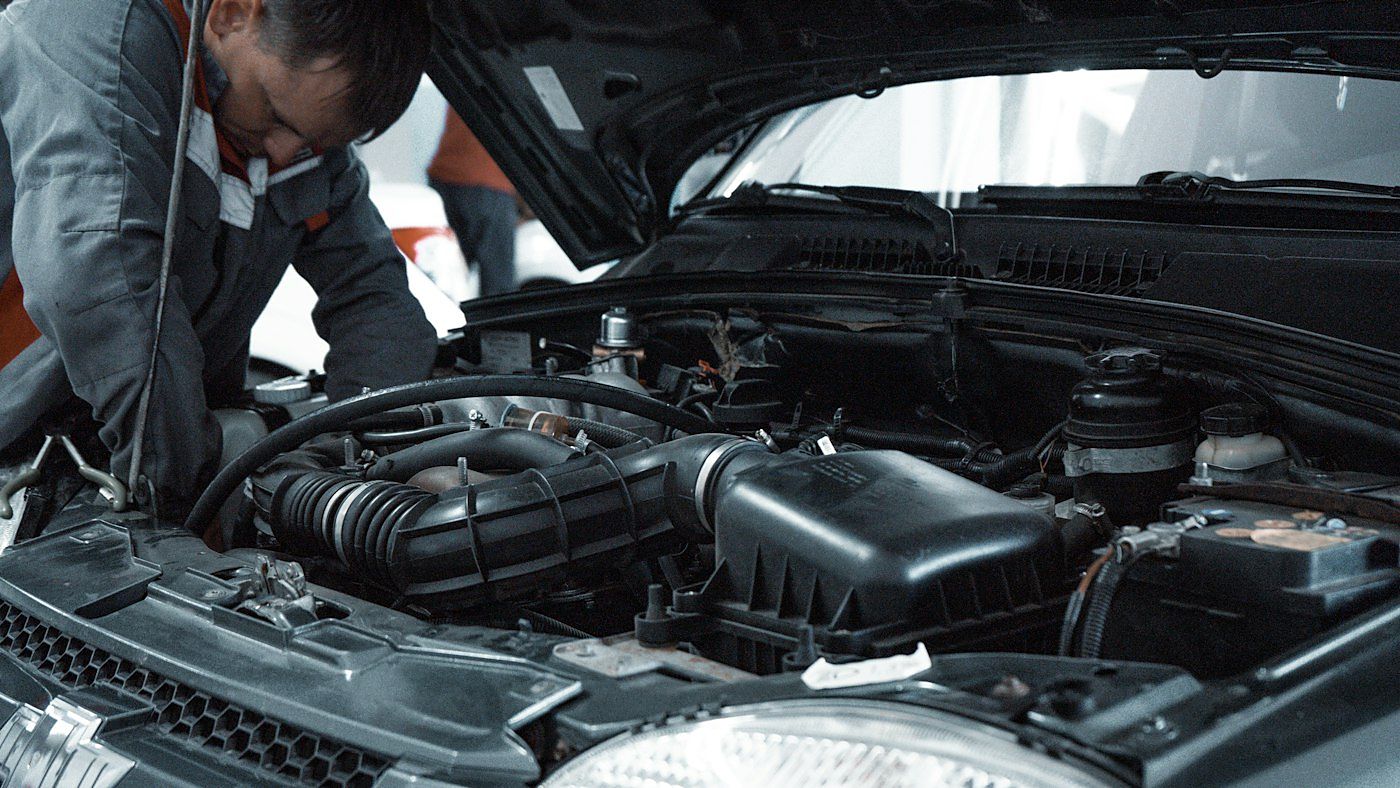 Técnico revisando el compartimento de un motor con el capó abierto